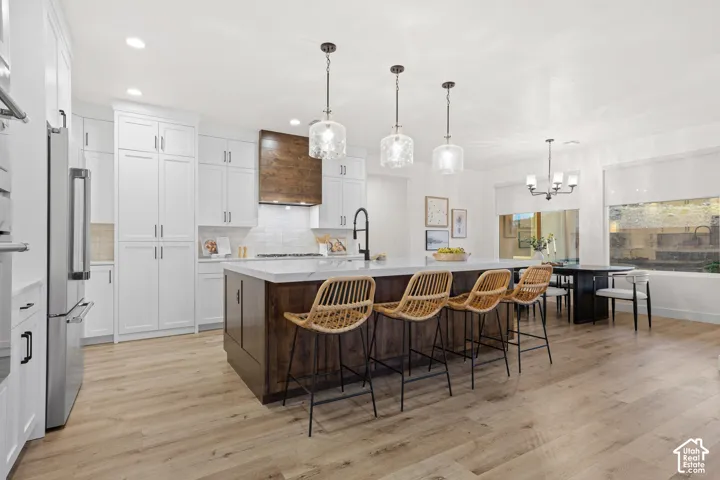 Gourmet kitchen with white cabinetry, wood-finish flooring, a center island featuring a wood-tone base, and pendant lighting