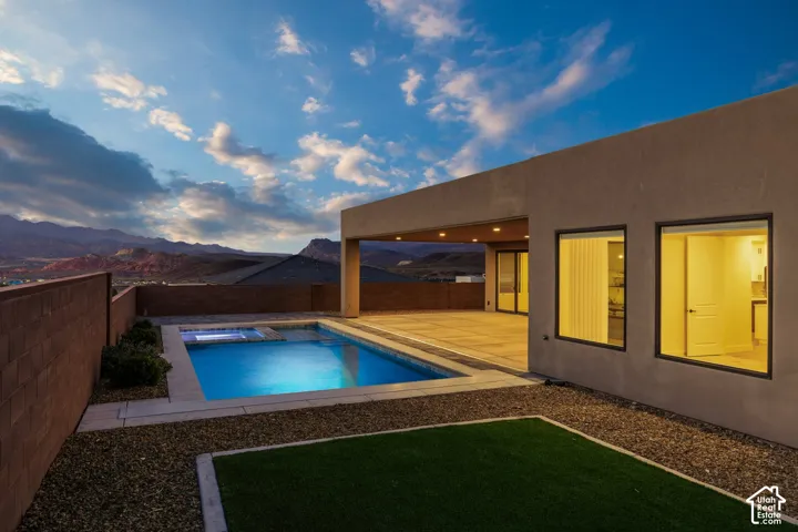 Stucco exterior with a covered patio, rectangular pool, and integrated spa