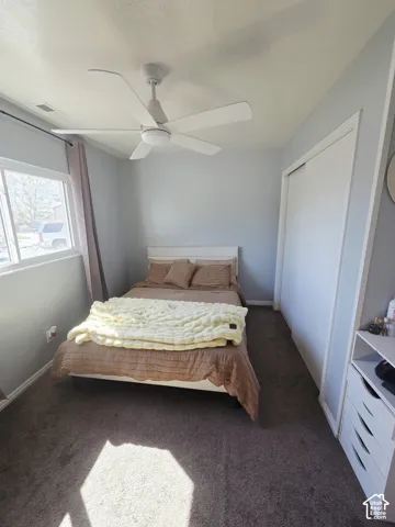 Wall-to-wall carpeting, ceiling fan with integrated lighting, sliding closet doors, and window with casing