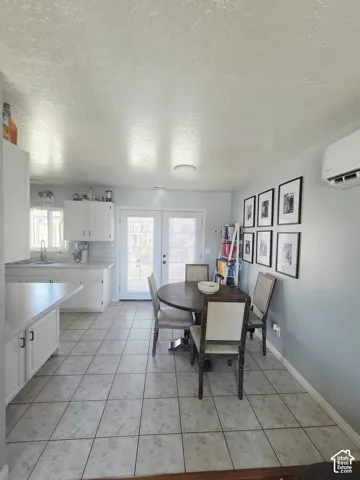 Open kitchen and dining area featuring white cabinetry, stainless steel appliances, tile flooring throughout, recessed and flush-mount ceiling lighting, and glass doors providing natural light and access to the rear patio