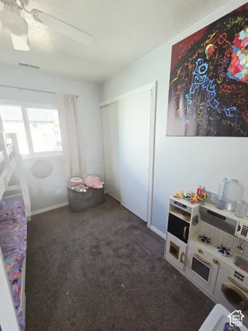 Recessed window, ceiling fan, sliding closet door, and carpeted flooring