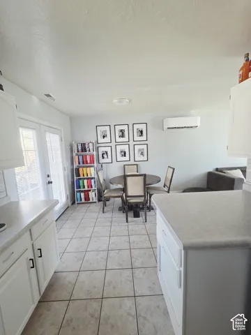 White cabinetry with dark hardware, light countertops, and tile flooring