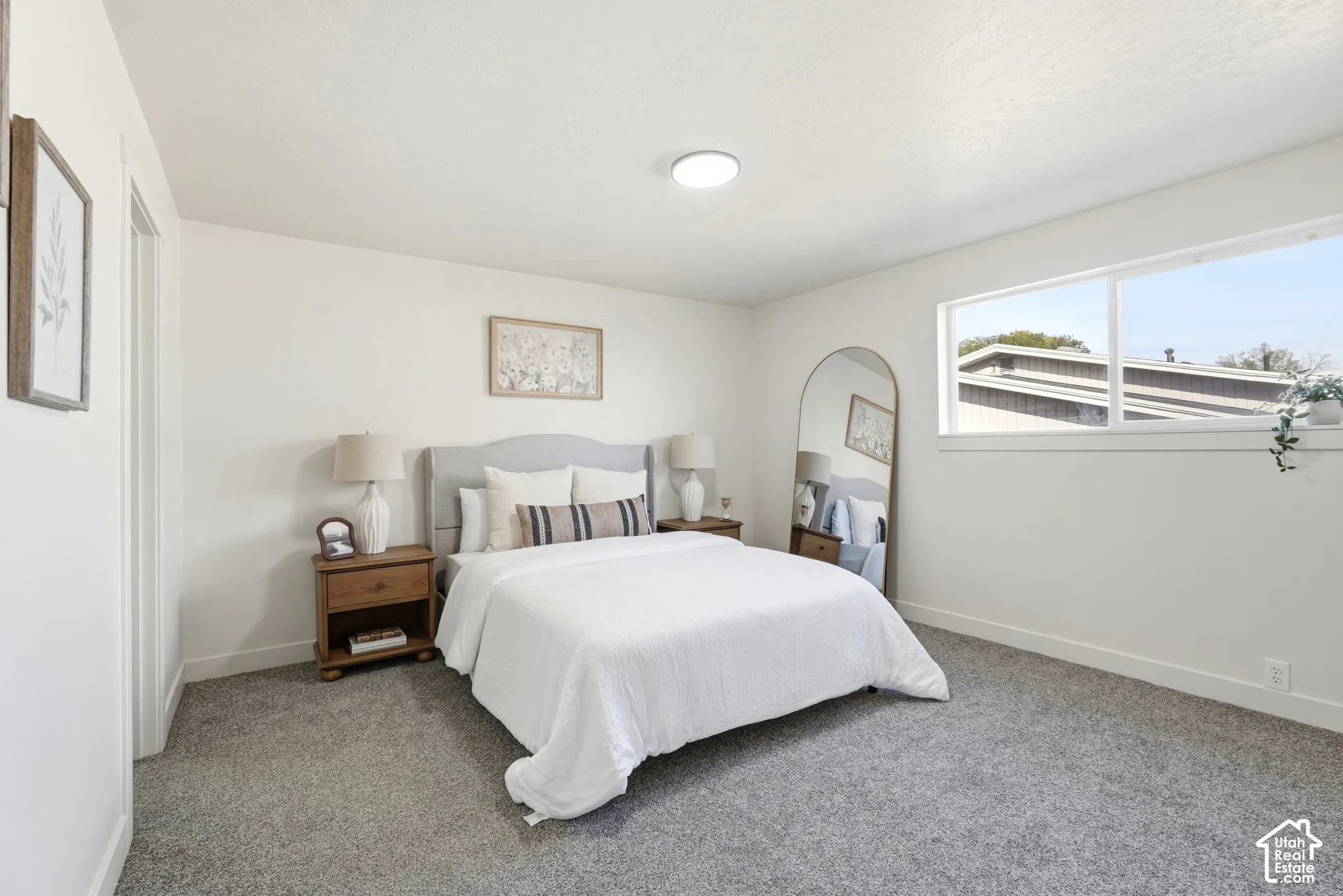 Recessed ceiling lighting, large window, neutral wall paint, gray carpeting, and a light wood-finish door frame