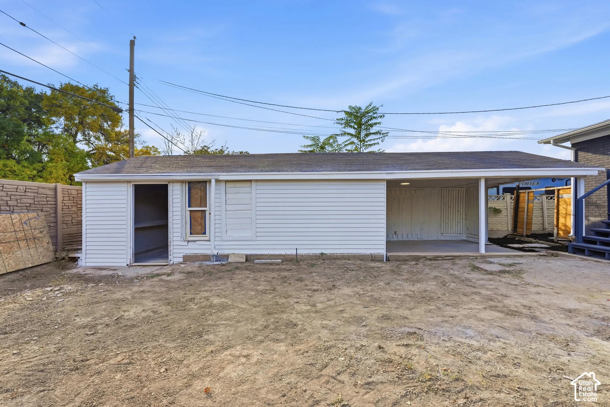 Detached structure with white siding and a carport
