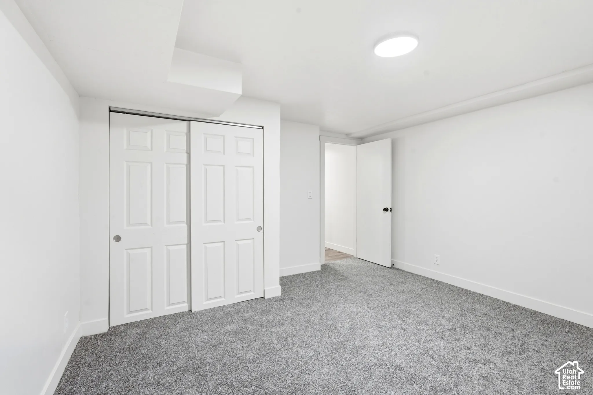 Recessed lighting, light gray carpeting, crisp white walls, and a white six-panel bi-fold closet door