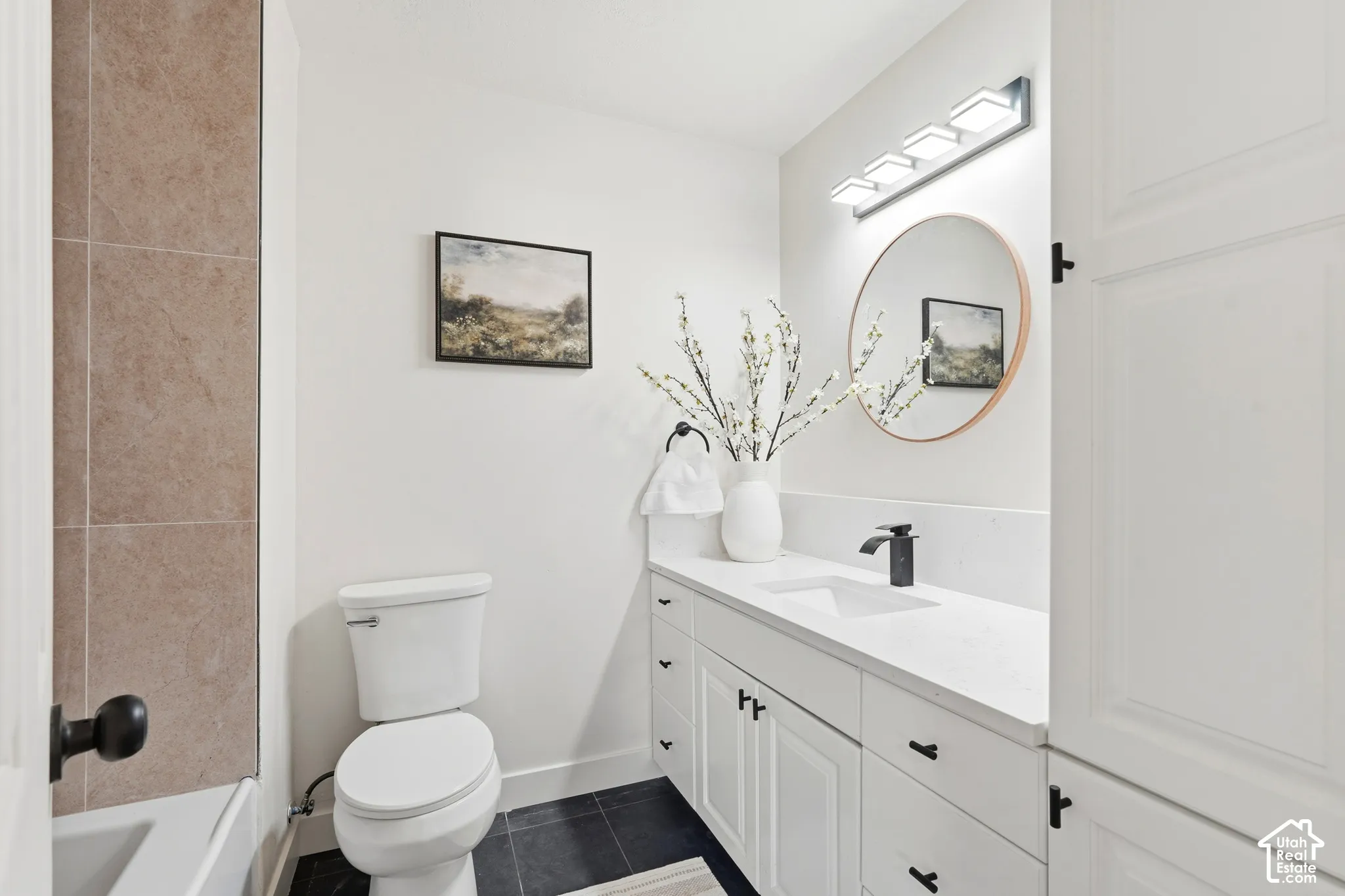 White vanity with a quartz countertop, integrated sink, and matte black faucet