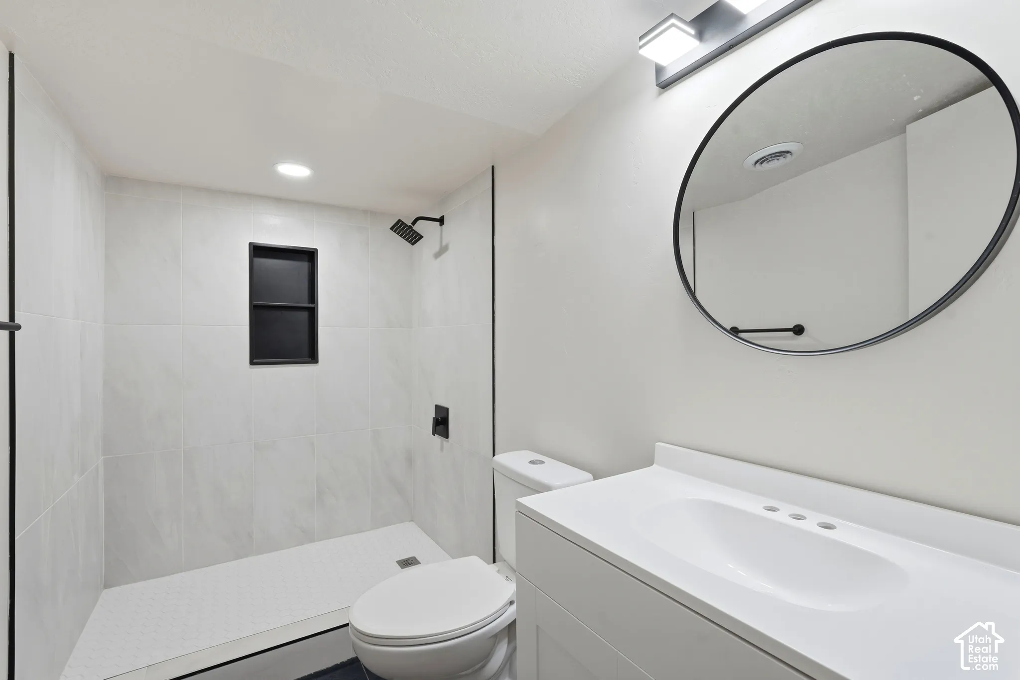 Walk-in shower with large format wall tiles, recessed niche, and matte black shower fixtures
