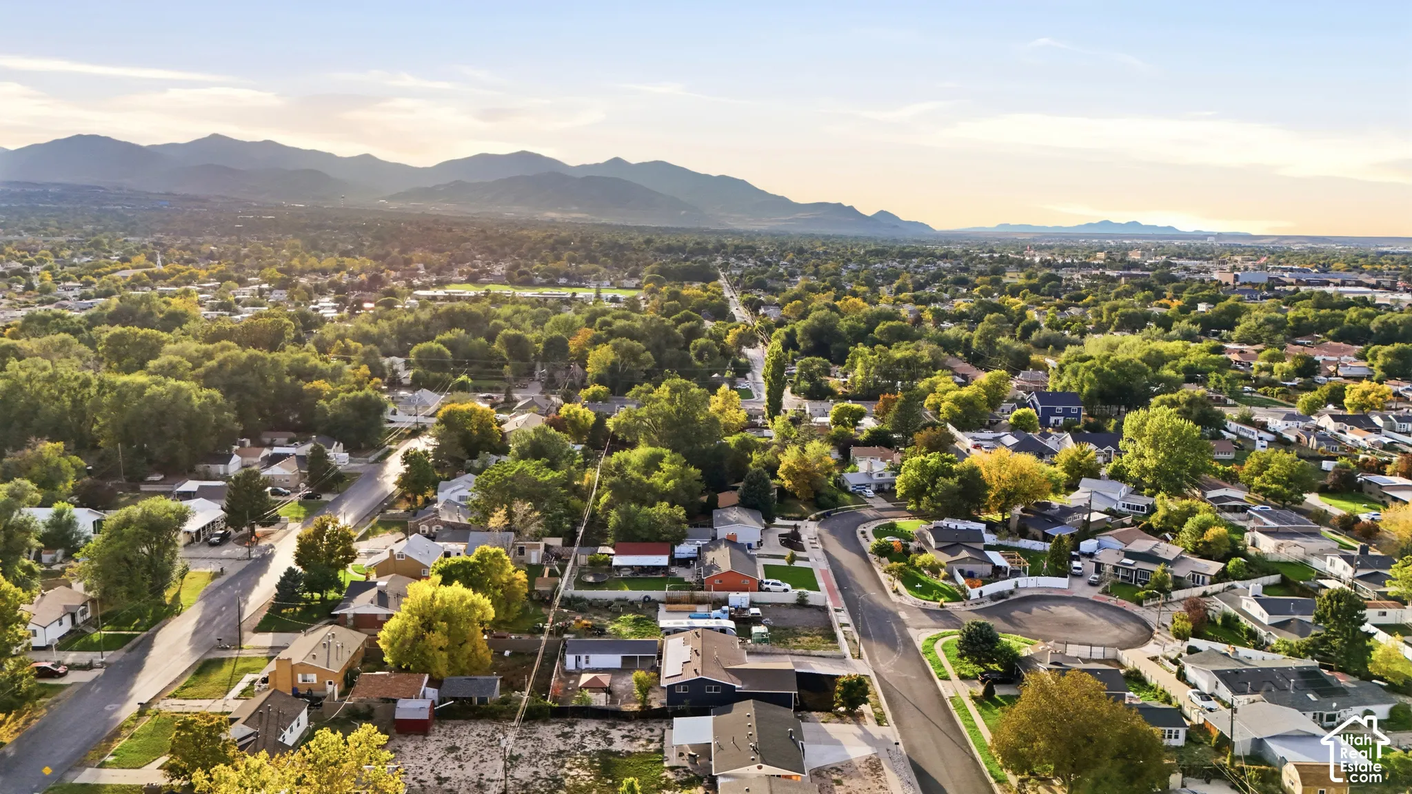 Expansive residential area featuring established homes, mature trees, and mountainous terrain in the distance