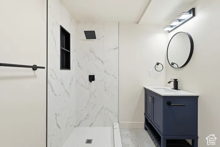 Walk-in shower with marble-look tile surround and black recessed niche