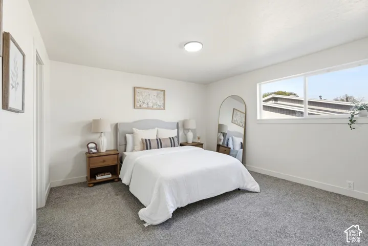 Recessed ceiling lighting, large window, neutral wall paint, gray carpeting, and a light wood-finish door frame