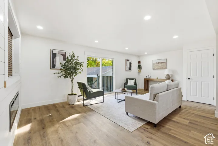Recessed lighting, wood-finish flooring, sliding glass door, white six-panel interior door, and a built-in electric fireplace