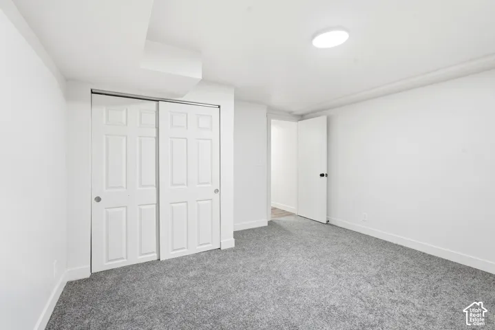 Recessed lighting, light gray carpeting, crisp white walls, and a white six-panel bi-fold closet door