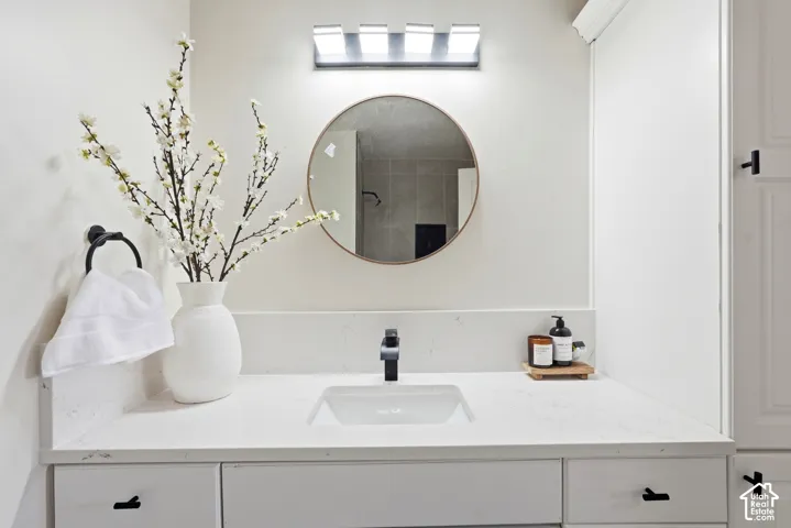 White vanity with an integrated sink, black modern faucet, round mirror, and wall-mounted light fixture