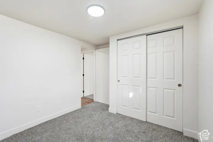 Recessed ceiling light fixture, white walls, gray textured carpeting, and white bi-fold closet doors