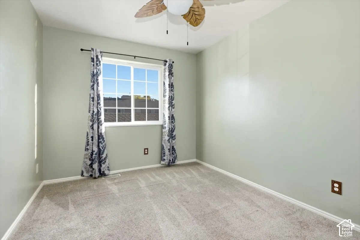 Pale green walls, plush gray carpet, and a multi-pane window