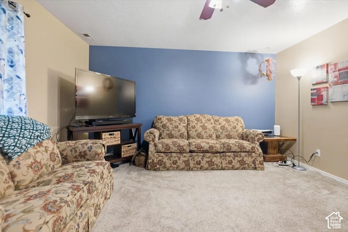 Wall-to-wall carpeting with painted walls and a ceiling fan