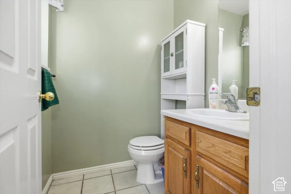 Pedestal sink with chrome faucet, light wood-finish vanity, and white storage cabinet