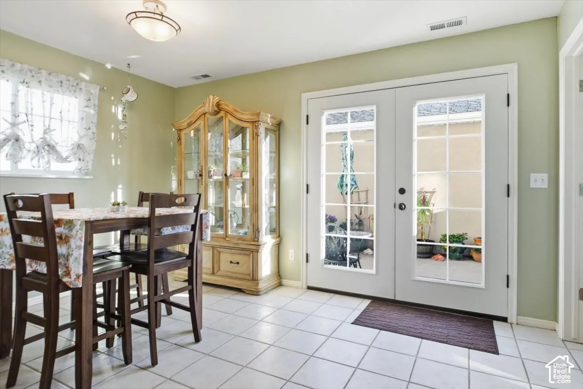 White tile flooring, double French doors, transom window, flush mount ceiling light fixture, and a light green wall finish