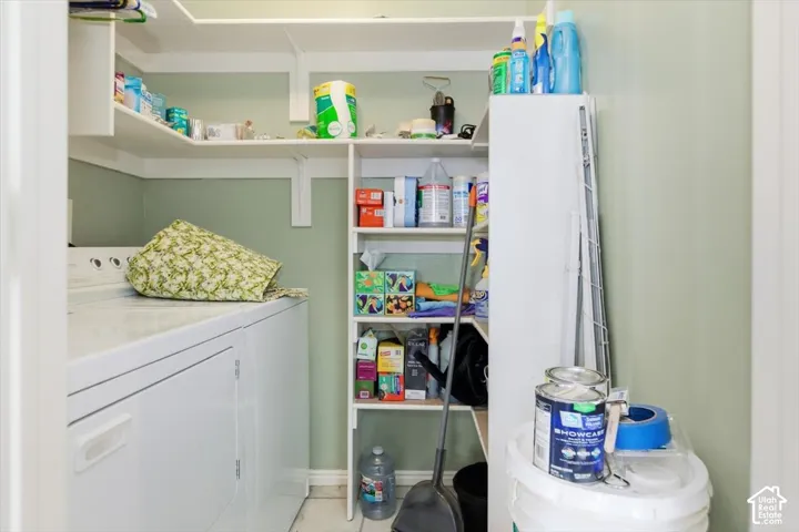 Laundry area with white appliances, built-in shelving, and pale green walls