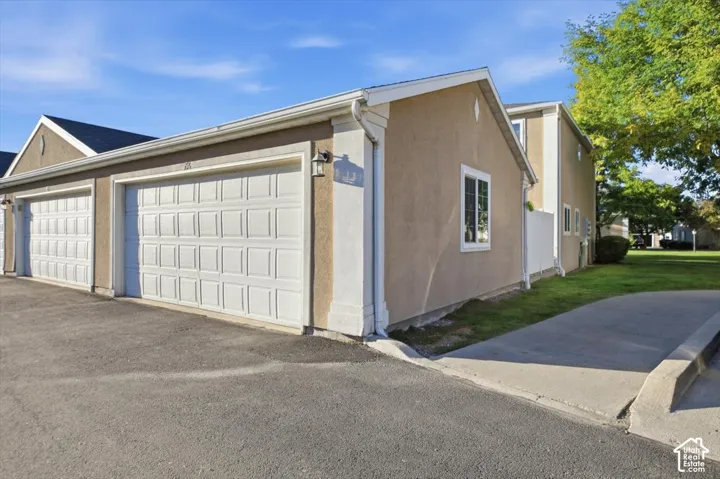 Stucco exterior with white trim, multiple garage doors, and a concrete driveway