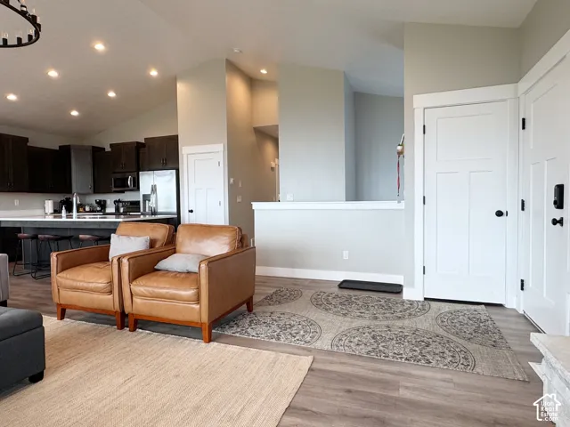 Open-concept living area with wood-finish flooring, vaulted ceilings, and recessed lighting