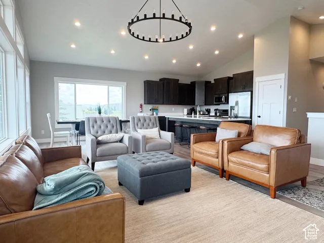 Vaulted ceiling with recessed lighting, large windows, wood-finish flooring, dark wood cabinetry, and a kitchen island with seating