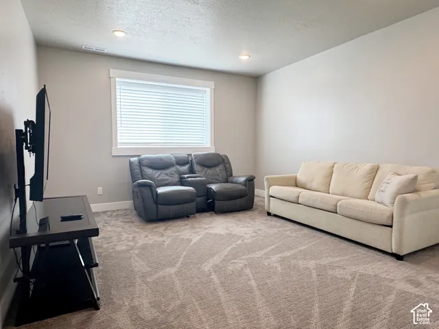 Recessed lighting, neutral wall tones, window with white blinds, and patterned carpeting