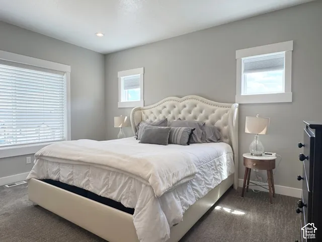 Wall-to-wall carpeting, recessed ceiling lighting, and multiple windows with white trim