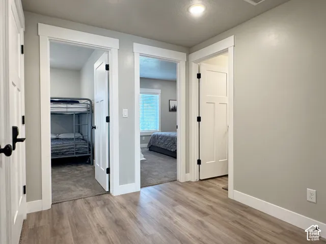 Wood-finish flooring, light grey wall paint, contemporary white trim, white paneled doors with black hardware, recessed ceiling lighting