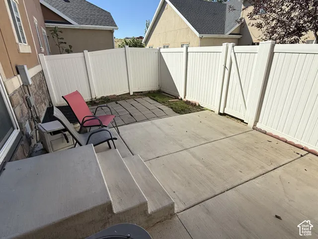 Private fenced patio featuring concrete steps and a paved surface