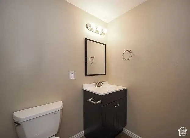 Vanity with dark wood-finish cabinetry, white countertop, and chrome faucet