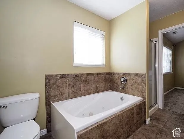 Built-in soaking tub with tiled surround, separate glass-enclosed shower, tile flooring, and a window with blinds