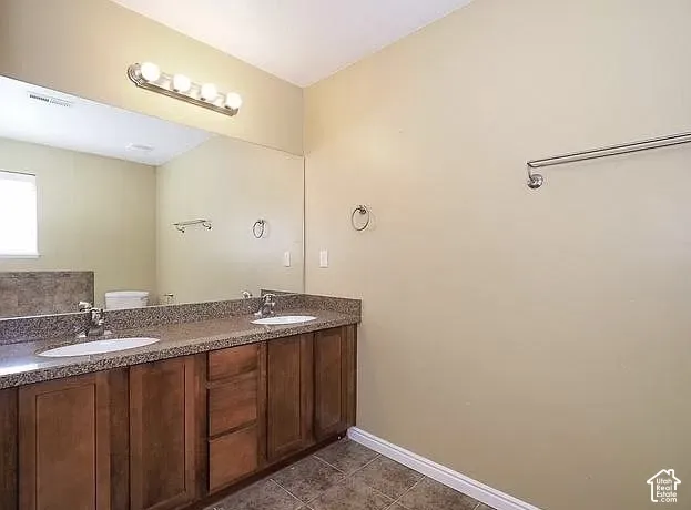 Dual vanity with under-mount sinks, wood-finish cabinetry, and a speckled countertop