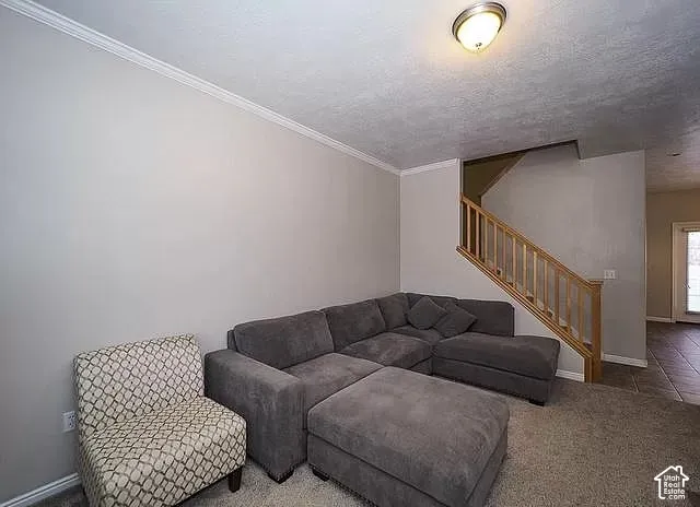 Recessed stairway, wood-finish railing, wall-to-wall carpeting, crown molding, and flush-mount ceiling light