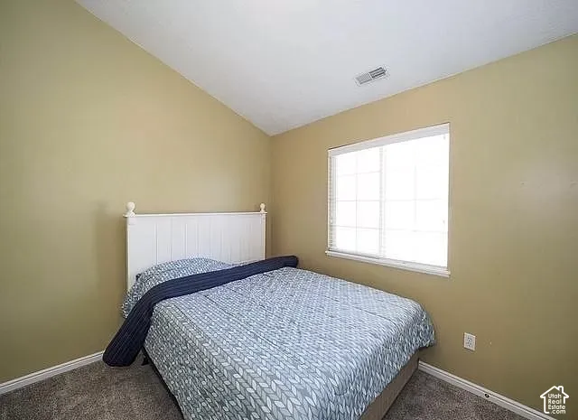 Vaulted ceiling, carpeted flooring, window with blinds, and painted walls