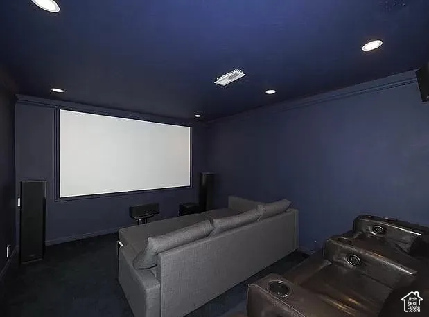 Dedicated media room featuring a large projection screen, recessed ceiling lighting, and dark wall finishes