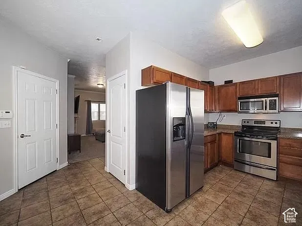 Kitchen featuring wood cabinetry, stainless steel appliances, and tiled flooring