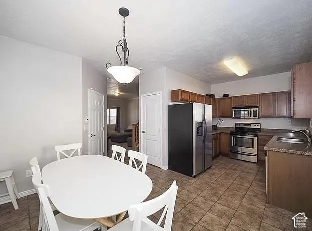 Kitchen featuring stainless steel appliances, wood-finish cabinetry, and tiled flooring