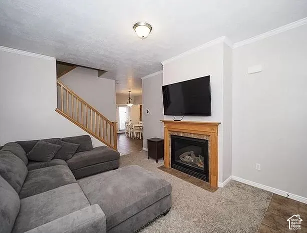 Built-in fireplace with a wood mantle and tile surround, complemented by crown molding and a staircase with wood railing