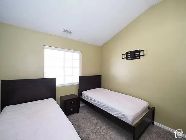Room featuring a vaulted ceiling, light-colored walls, and textured carpeting