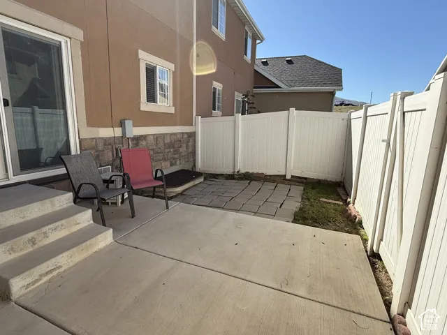 Concrete patio with steps, vinyl privacy fencing, and stone veneer foundation detailing