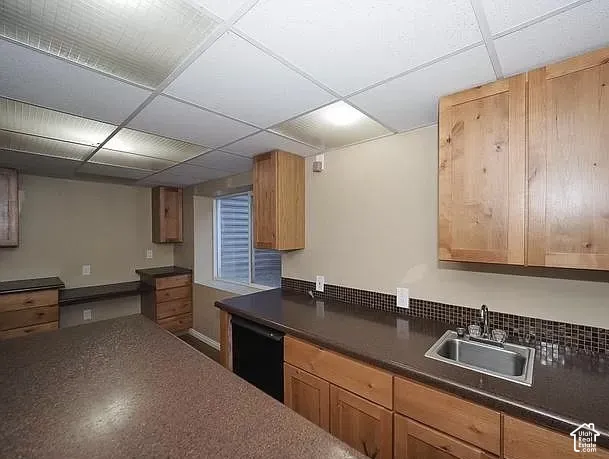 Functional kitchenette featuring a stainless steel sink, wood cabinetry, and contrasting countertops