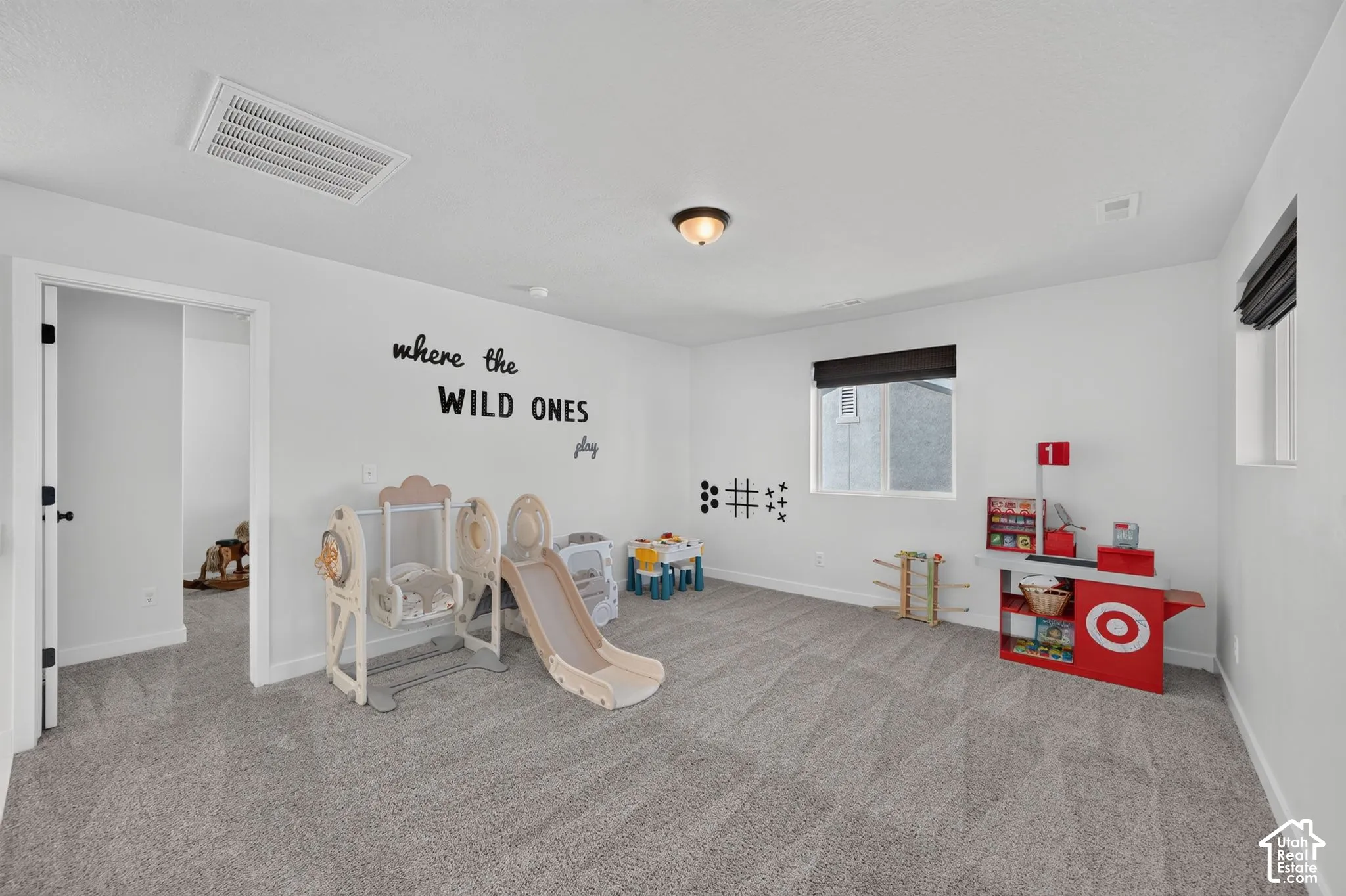 Spacious room with light gray carpeting, neutral white walls, and a recessed ceiling light