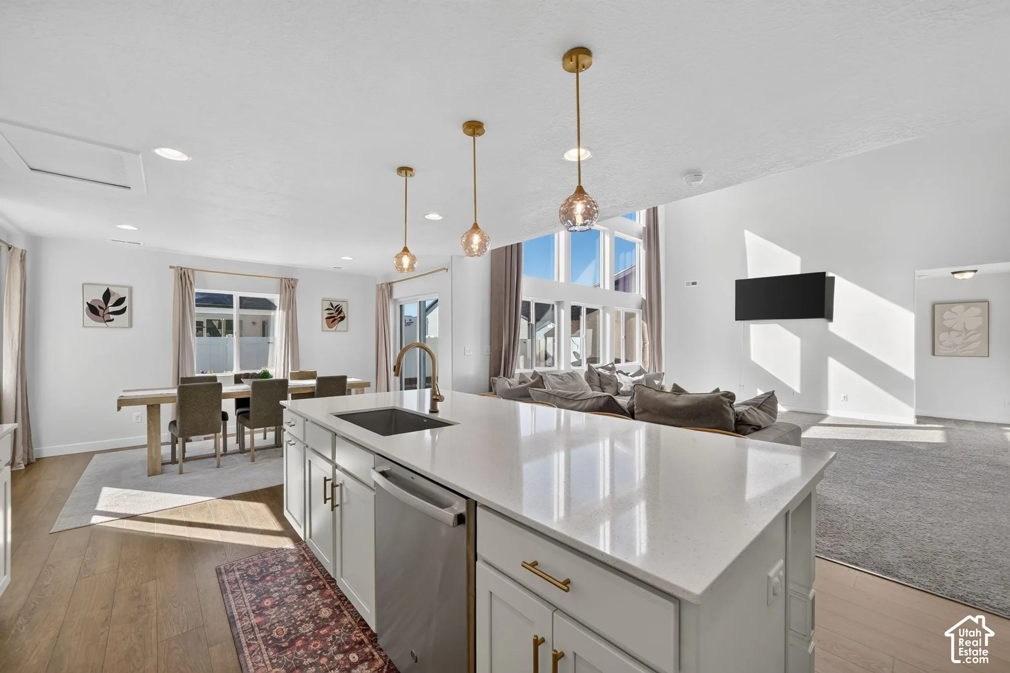 Kitchen island with a quartz countertop, integrated sink, and stainless steel dishwasher