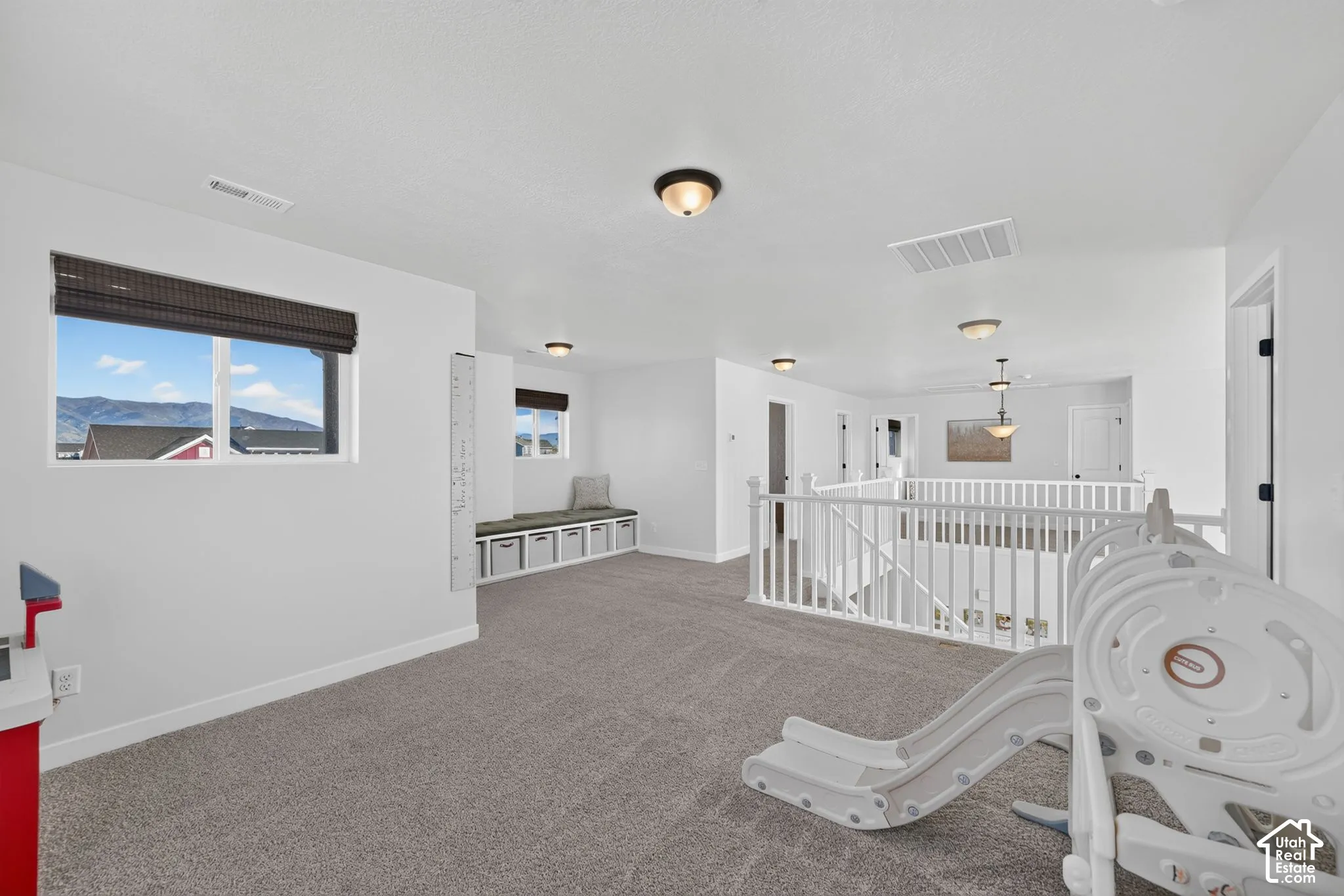 Spacious bonus room featuring neutral carpeting, abundant natural light from large windows with mountain vistas, recessed ceiling lighting, and built-in white cabinetry