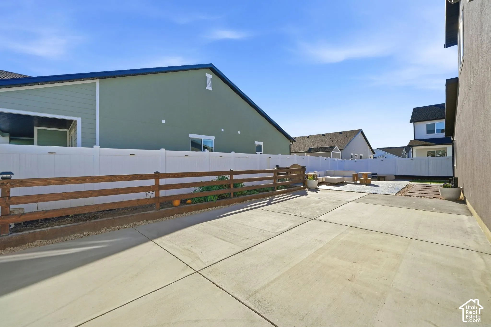 Expansive concrete patio with a wood-rail fence and privacy fence