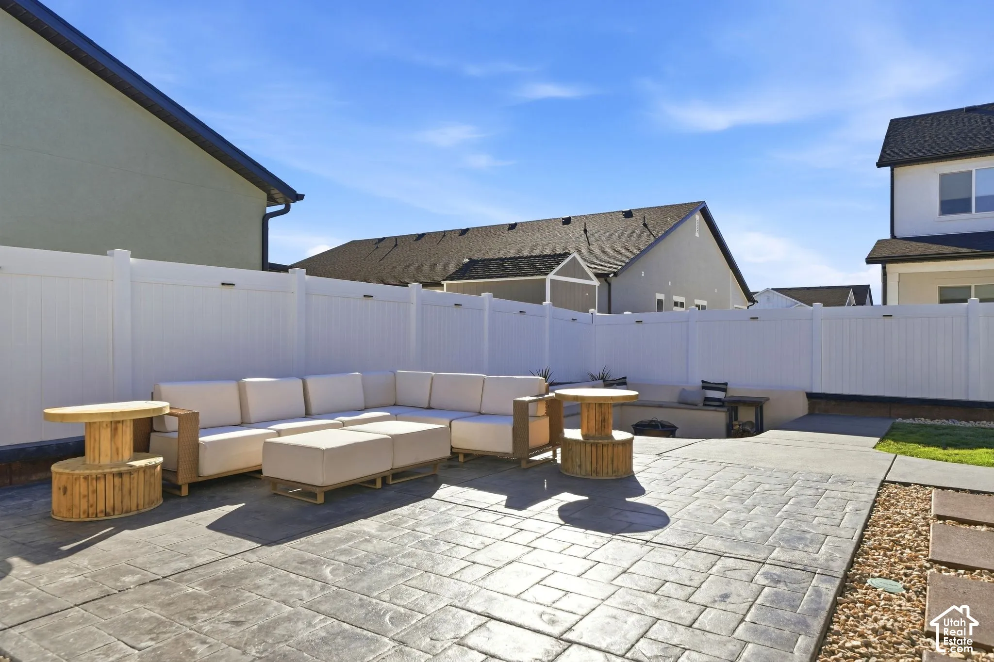 Stamped concrete patio, white vinyl fencing, built-in concrete bench, gravel landscaping, and lush green lawn