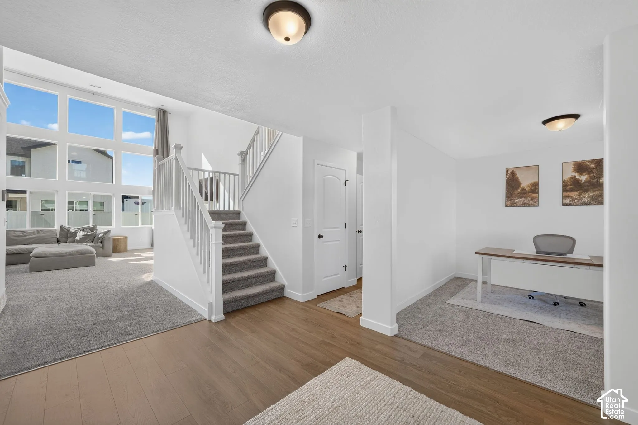 Two-story entry with wood-finish flooring, staircase with white railings, and high ceilings