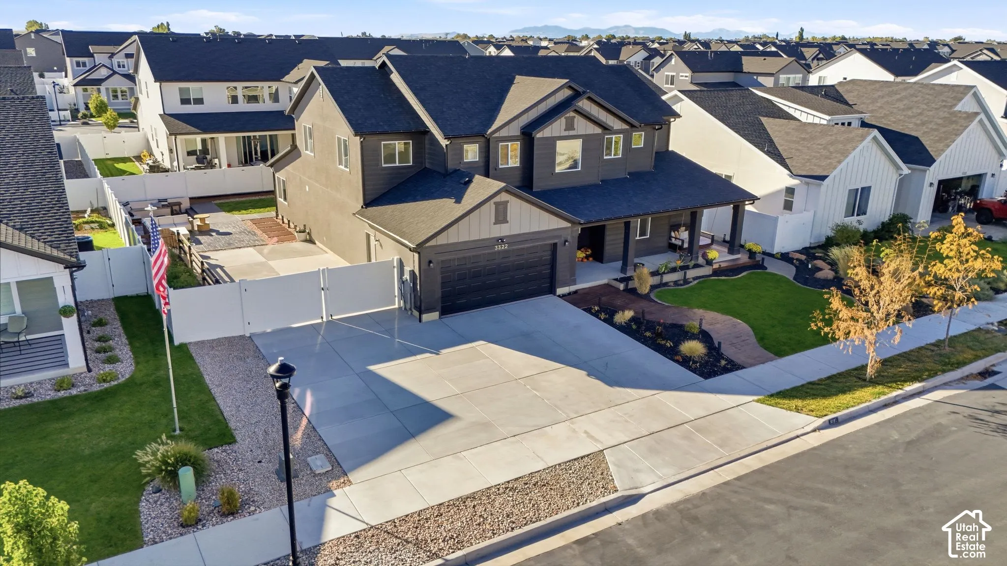 Two-story exterior with dark gray siding and white trim, featuring a covered front porch, a two-car garage, and a concrete driveway