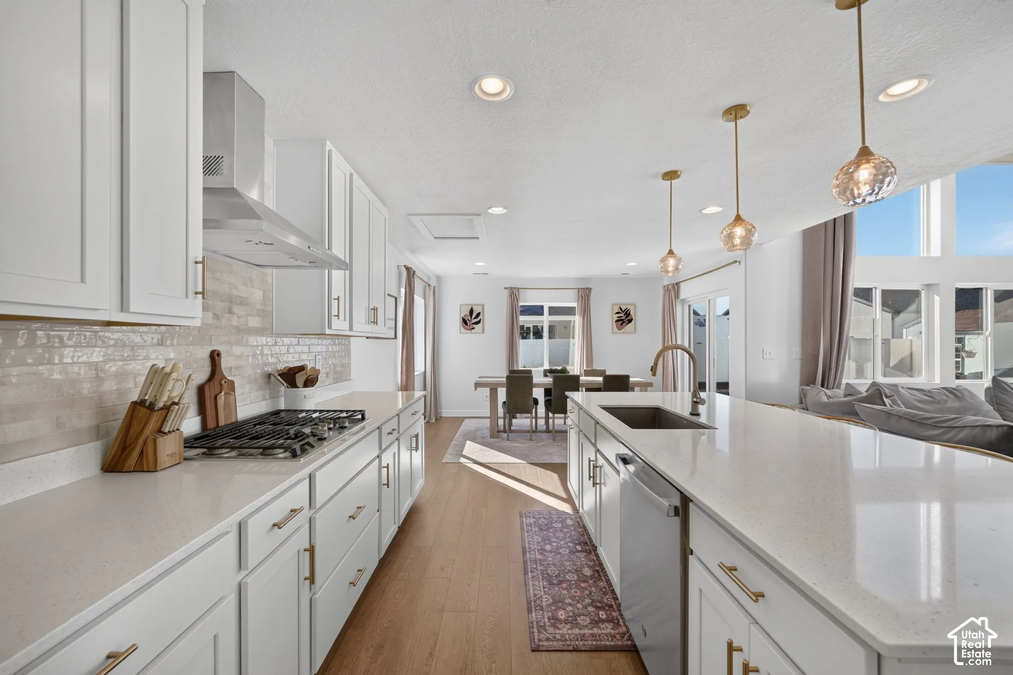 Kitchen featuring white shaker cabinetry, light-toned countertops, a stainless steel gas range, and wood-finish flooring